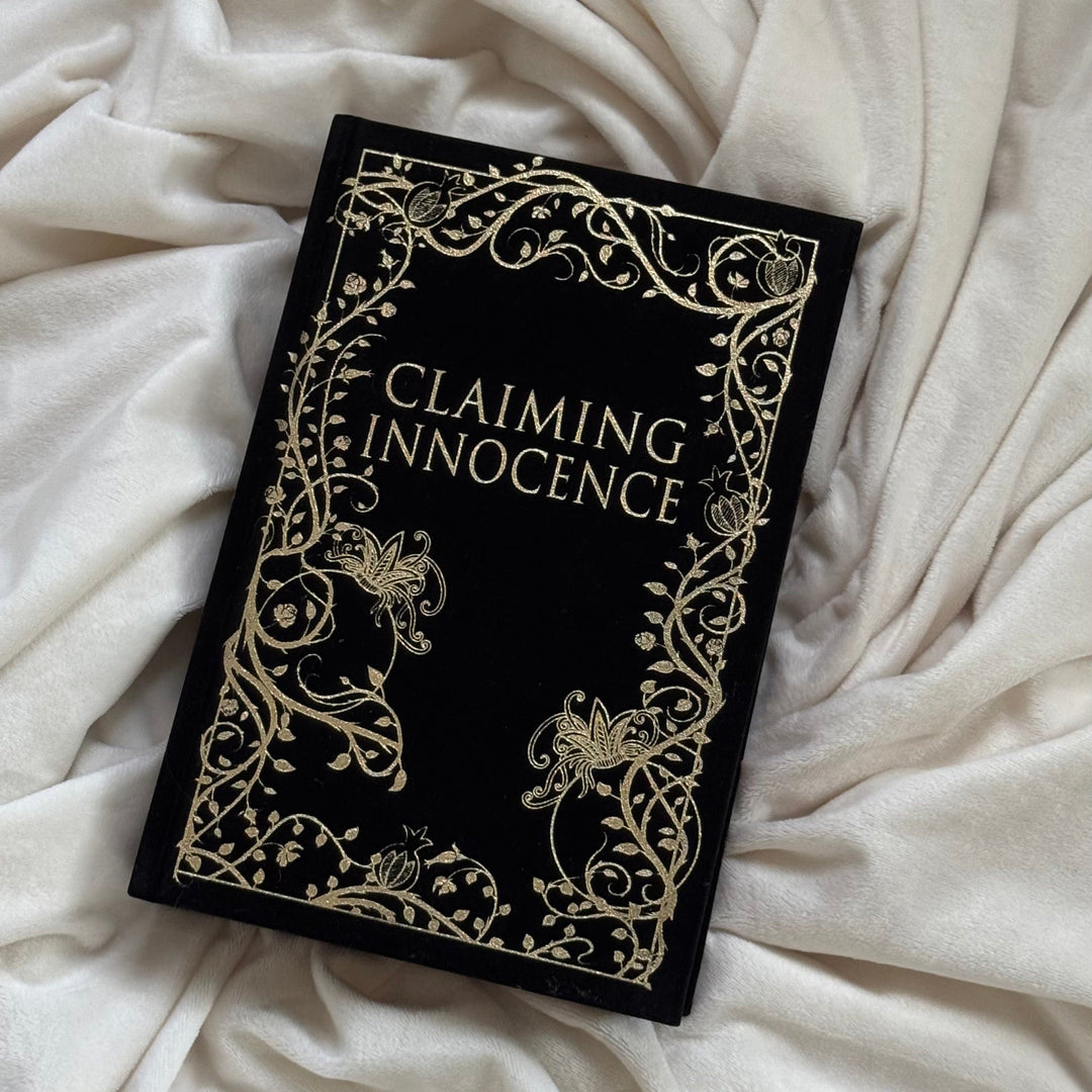 Book titled 'Claiming Innocence' with decorative cover on a white fabric background