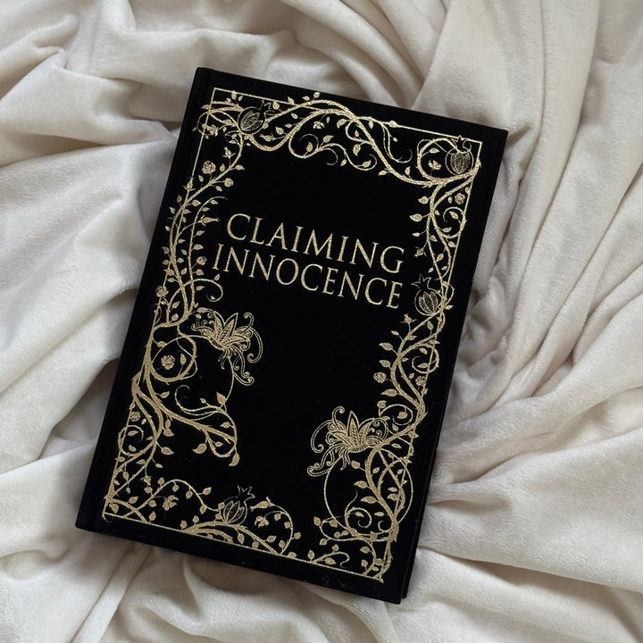 Book titled 'Claiming Innocence' with decorative cover on a white fabric background